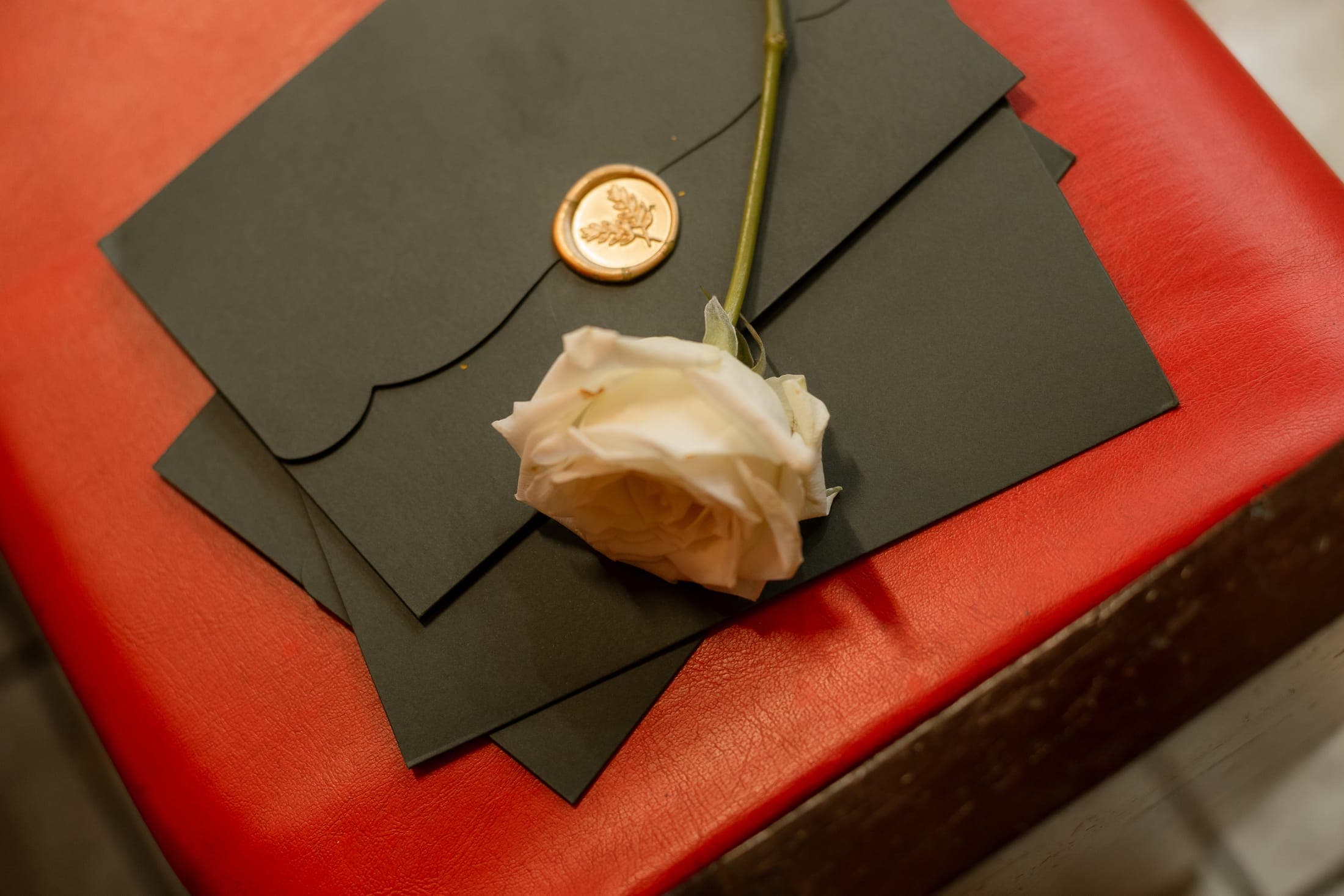 Convite do casamento com uma rosa dourada, ao lado das alianças