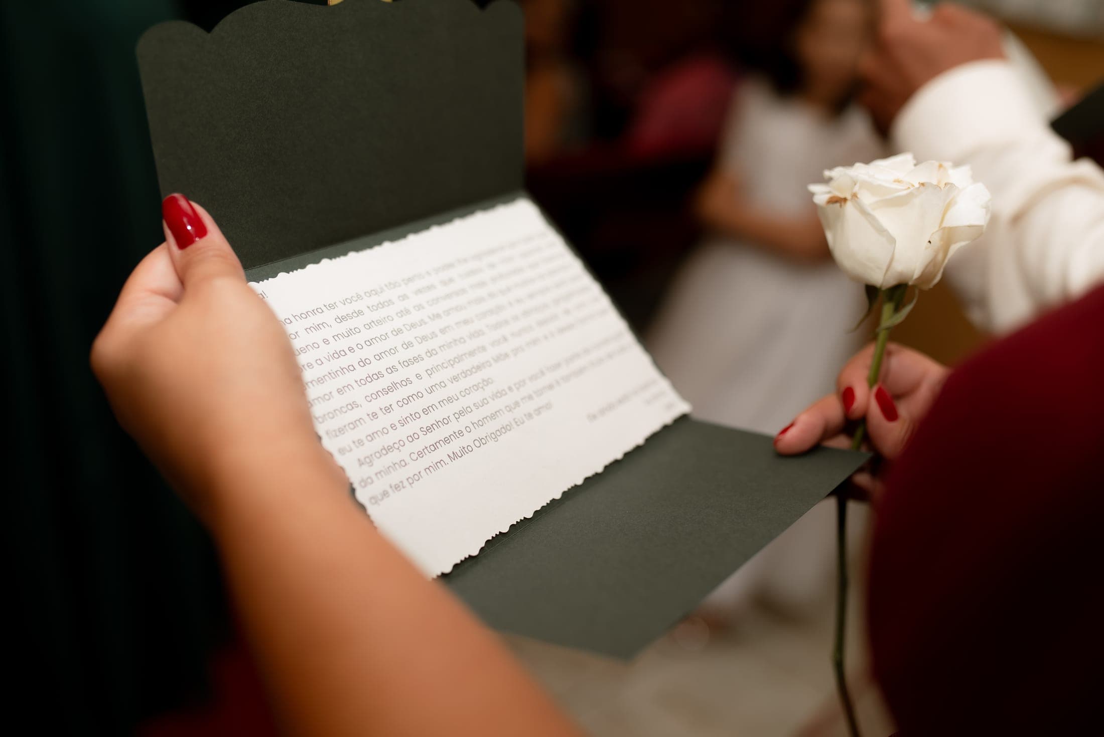 Mãos segurando a carta aberta e uma rosa branca