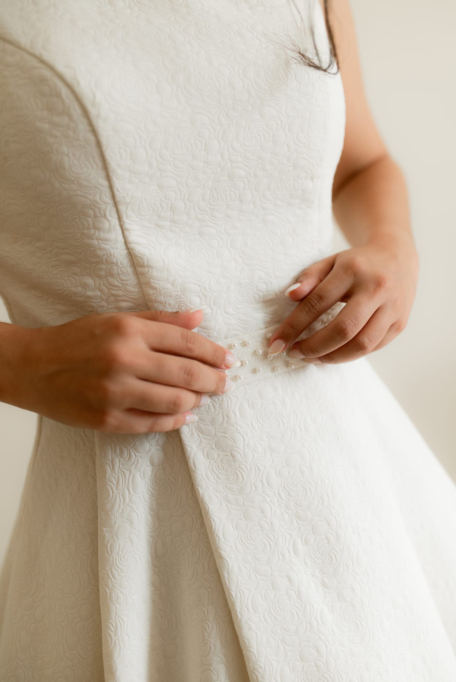 Mãos fechando os últimos botões do vestido