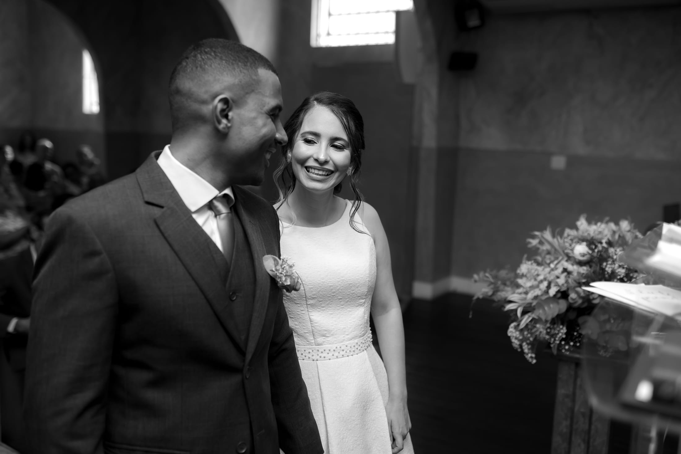 Aline e Leonardo rindo juntos na igreja, em preto e branco